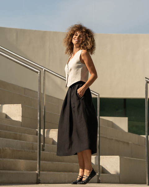 The menique women's linen est AVA in natural color and balck Sophia skirt. The woman is smiing