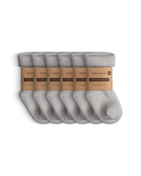 Six pairs of light gray sherpa fleece socks for kids, folded neatly with Menique brown paper labels marked ‘Premium Quality.