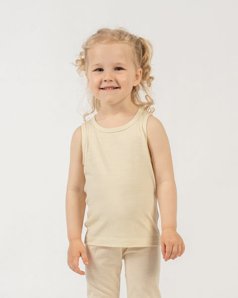 Young child wearing a natural merino wool menique sleeveless top and pants on a white background