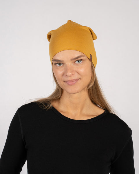 Woman wearing yellow merino wool beanie with black base layer, front view.