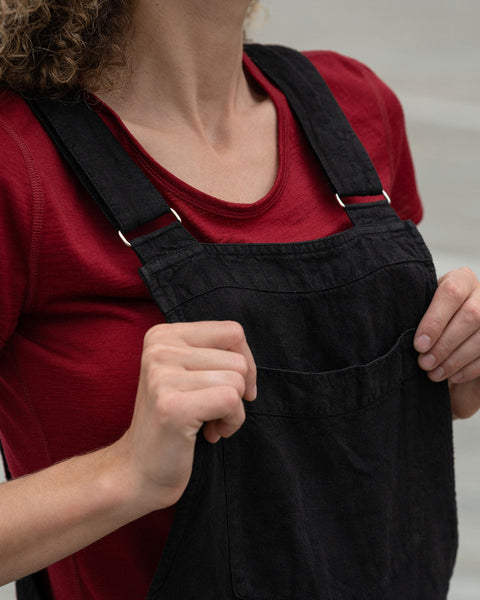Close-up of a woman holding to her pure black linen jumpsuit nicci.