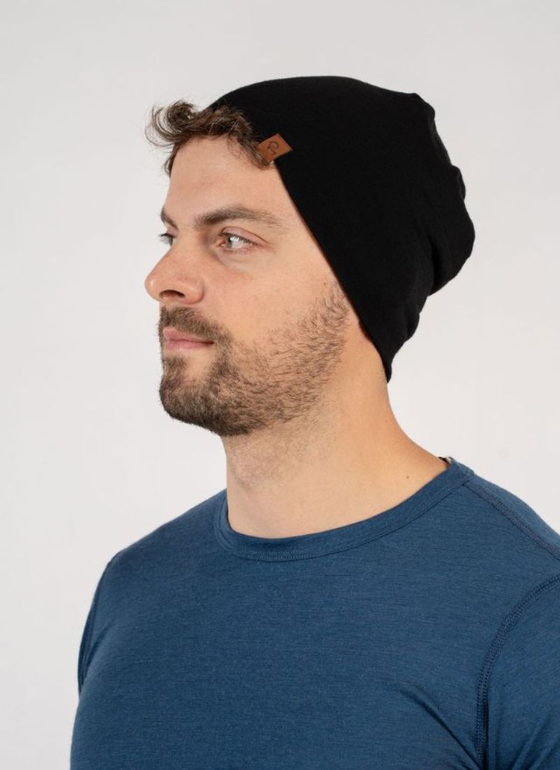 Man wearing a black beanie and blue shirt against a white background