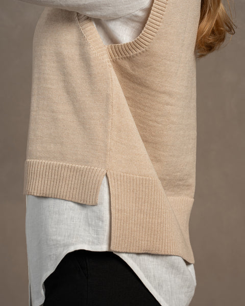 The side of the merino wool knitted vest ISLA in beige color. The front is a little shorter than the back, as visible in the picture. The vest has slits on both sides.