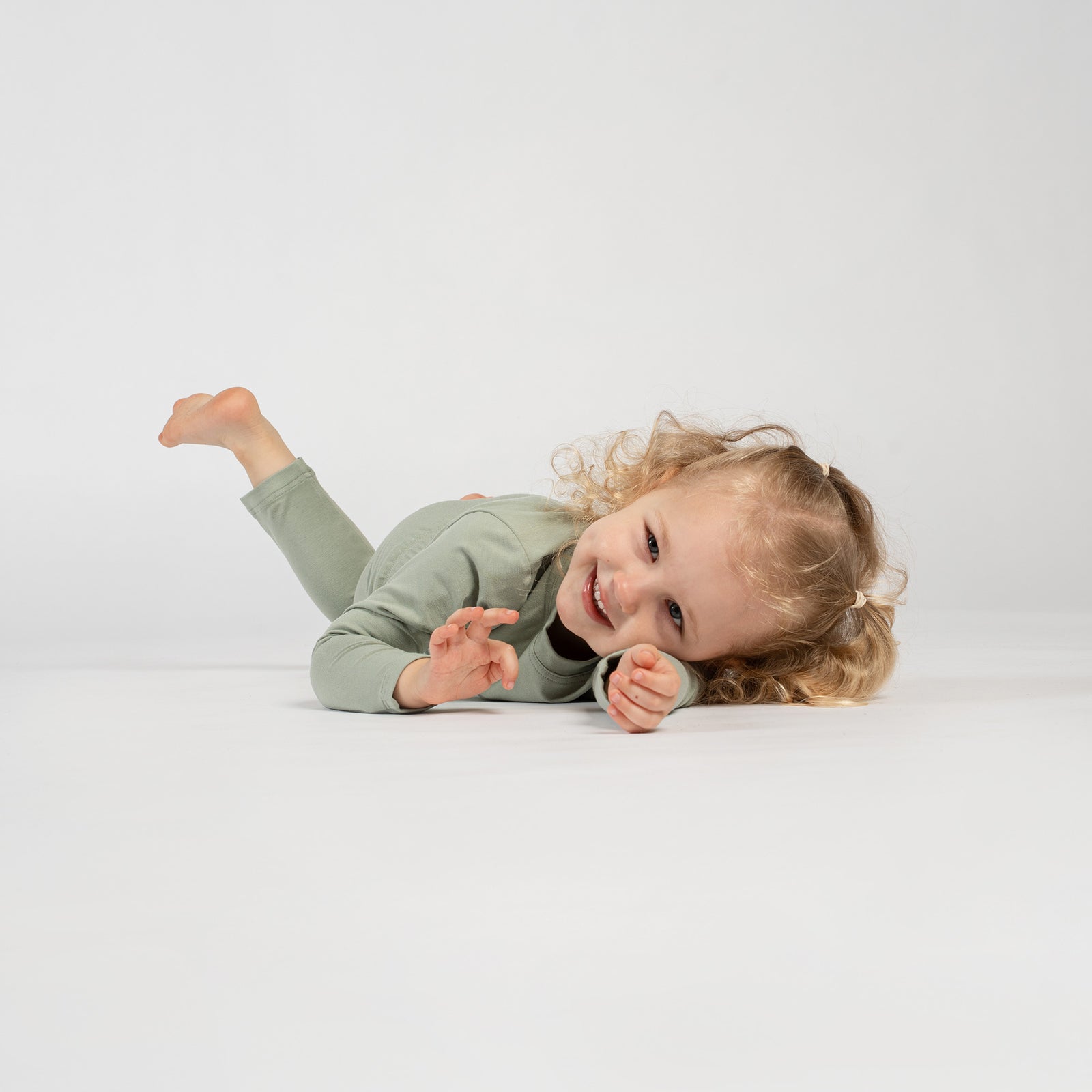 Two children in soft pajamas cuddling a teddy bear while sleeping on a bed with light blue bedding.