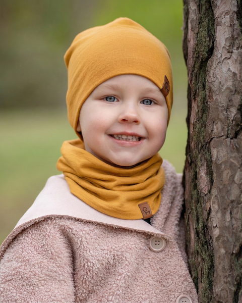 Child wearing yellow merino wool beanie and neck gaiter outdoors, soft breathable accessories for kids in cool weather.