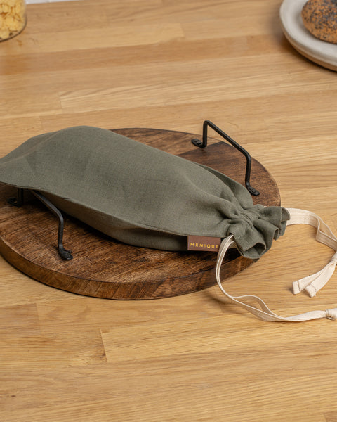 Stone Green drawstring bag on a wooden surface with 'MENIQUE' branding.