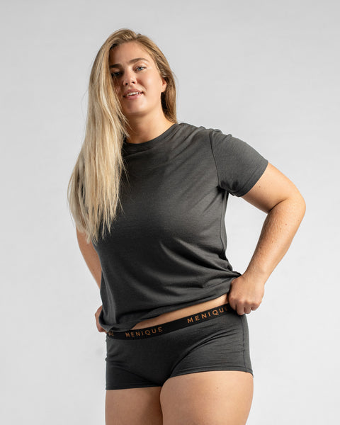 Three-quarter view of a model with long blonde hair wearing a grey short-sleeve t-shirt and grey boy-short underwear, holding the waistband.