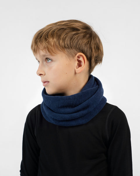 A young boy in profile wearing a dark blue knit infinity scarf and a black long-sleeved top.